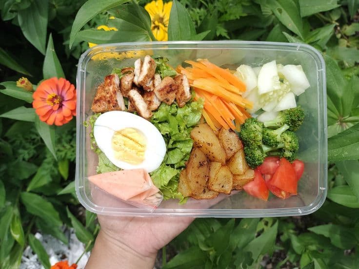 Hộp nhựa trong suốt đựng salad healthy meal với ức gà, trứng luộc và rau củ tươi